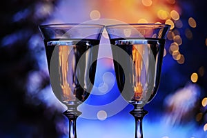 Two glasses with champagne sparkling wine on a festive blue background with lights and bokeh.