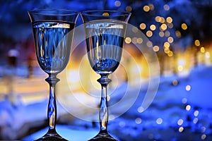 Two glasses with champagne sparkling wine on a festive blue background with lights and bokeh.