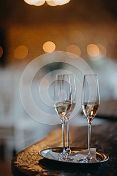 Two glasses of champagne on table on blurred background. Wedding, party, celebratory toast.