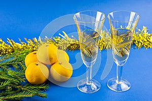 Two glasses of champagne, tangerines and yellow Christmas tinsel