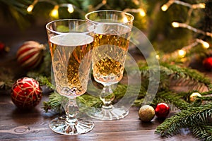 Two glasses of champagne on the wood table with christmas balls and fir branches.