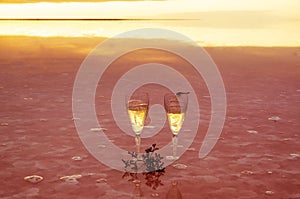 Two glasses of champagnein the water of pink lake with reflaction, at sunrise, Ukraine Valentine`s Day