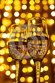 Two glasses with champange on a dark background with LED lights garland. New year and Christmas. Copy Space. Soft focus.