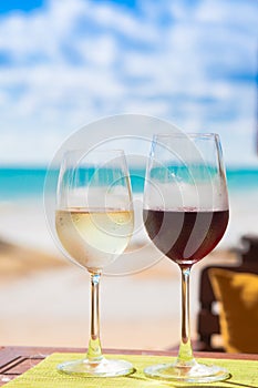 Two glasses of chilled white and red wines on table near the beach photo