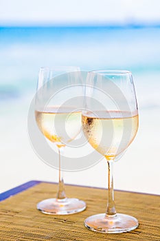 Two glasses of chilled white wine on table near the beach photo