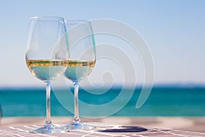 Two glasses of chilled white wine on table over Garla Lake backgound