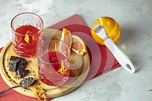 Two glasses of chocolate red orange negroni, alcoholic bitter cocktail served by ingredients on the light gray table