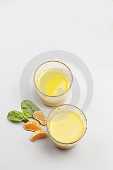 Two glasses with citrus juice. Tangerines on table