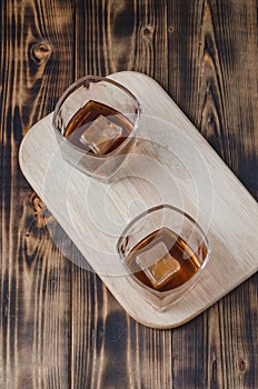 Two Glasses of cognac with ice cubes on a wooden table/Two Glasses of cognac with ice cubes on a wooden table. Top view