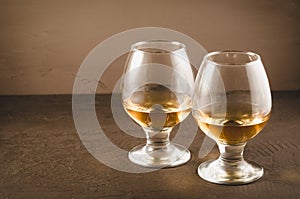 two glasses with cognac/two glasses with cognac on a dark stone background, selective focus