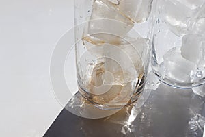 Two glasses of cola with ice cubes on white table. Top view, copy space. Hard light, shadow.  Refreshing summer drink