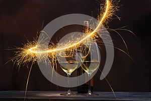 Two glasses containing wine with wine bottles are decorated with sparkling fireworks