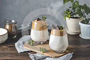 Two glasses with Dalgona frothy coffee trend korean drink latte espresso with coffee foam, decorated by thyme and dark chocolate.