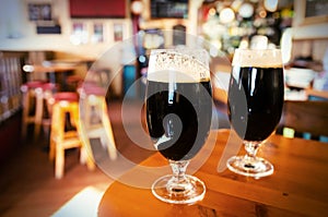 Two glasses of dark beer in a bar