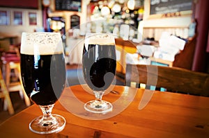 Two glasses of dark beer in a bar