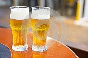 Two glasses of draft beer on wooden table top