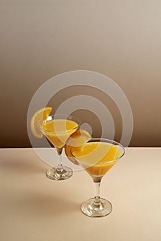 two glasses filled with orange juice and sliced oranges on a table