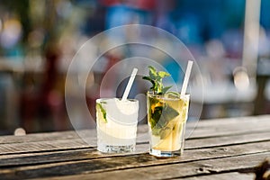 Two glasses fresh alcoholic cooling cocktail in summer on the terrace of a cafe. A refreshing mojito with ice, mint and