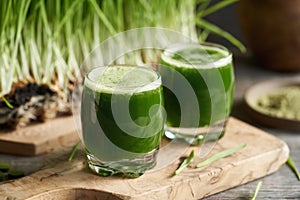 Two glasses of green barley grass juice with freshly grown blades