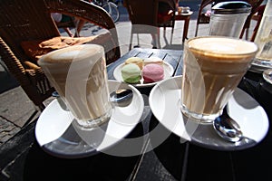 Two glasses of latte macchiato with macaron french dessert