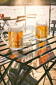 Two glasses of light beer with foam on a wooden table.On a boat. Garden party. Natural background. Alcohol. Draft beer. Landscape,