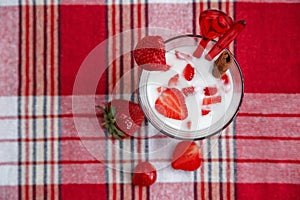 Two Glasses of Milk Cocktail,Red Fresh Strawberries with Plastic Spoons and Cinnamon on the Check Tablecloth.Breakfast Organic