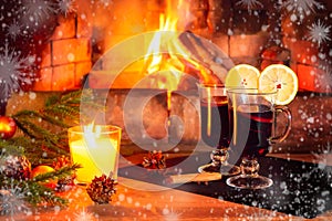 Two glasses with mulled wine, a candle, fir branches with decorations on a wooden table against the background of a