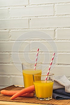 Two glasses of orange and carrot juice with space for text. paper stripped straws