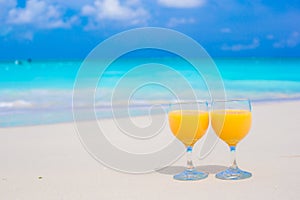 Two glasses of orange juice on tropical white beach