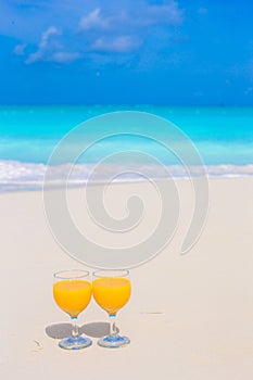 Two glasses of orange juice on tropical white beach