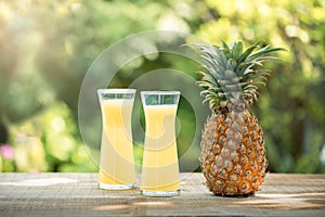 Two glasses of pineapple juice with a raw pine apple