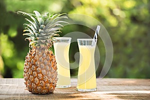 Two glasses of pineapple juice with a raw pine apple