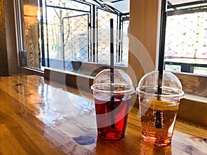 Two glasses of plastic red and yellow refreshing cold tasty sweet raspberry strawberry cherry orange peach lemon fruit lemonade