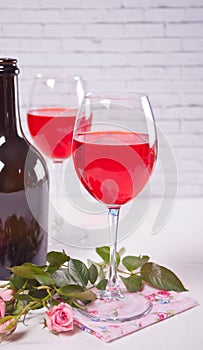 Two glasses with red grape wine with bottle and roses on the background. Romantic dinner concept