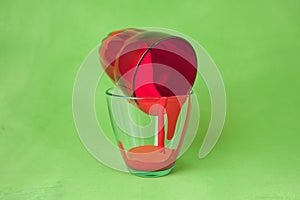Two glasses with red paint on a green background