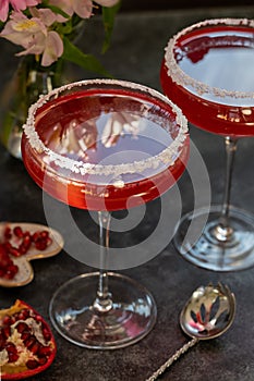 Two glasses with red pomegranate cocktail. Party, mixed colourful cocktail. Dark background, creative soft focus.