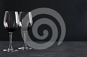 Two glasses of red thick and heavy, mouthfeel wine on the rustic surface agaisnt black background