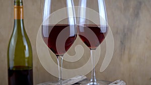 Two glasses of red wine. Alcoholic drink in a glass. A bottle of wine. Wooden background.