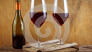 Two glasses of red wine. Alcoholic drink in a glass. A bottle of wine. Wooden background.