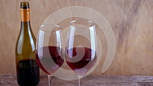 Two glasses of red wine. Alcoholic drink in a glass. A bottle of wine. Wooden background.