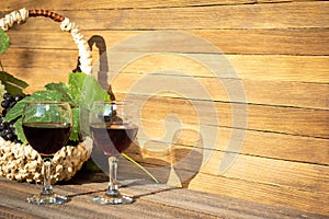 Two glasses of red wine and a basket of grapes on a wooden background on a Sunny day with copy space.