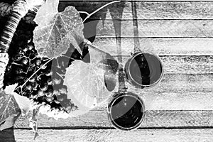 Two glasses of red wine and a basket of grapes on a wooden background on a Sunny day top view