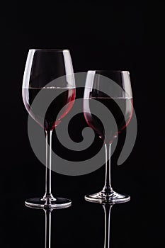 Two glasses with red wine on a black background. Wine on the dark