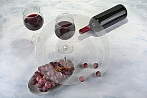 Two glasses of red wine with bottle and grapes.