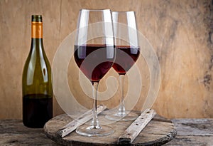 Two glasses of red wine. The bottle of wine is on the table. Wine background. Still life. Alcoholic drink in a glass. Wooden