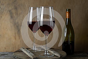 Two glasses of red wine. The bottle of wine is on the table. Wine background. Still life. Alcoholic drink in a glass. Wooden