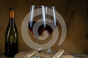 Two glasses of red wine. The bottle of wine is on the table. Wine background. Still life. Alcoholic drink in a glass. Wooden