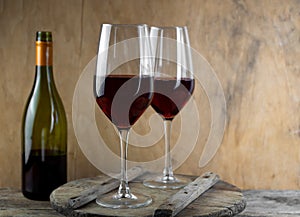 Two glasses of red wine. The bottle of wine is on the table. Wine background. Still life. Alcoholic drink in a glass. Wooden