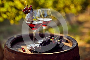 Two glasses of red wine with a bottle on a wooden barrel