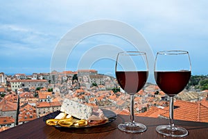 Two glasses of red wine with charcuterie assortment on view of Dubrovnik red roofs. Glass of red wine with different snacks -